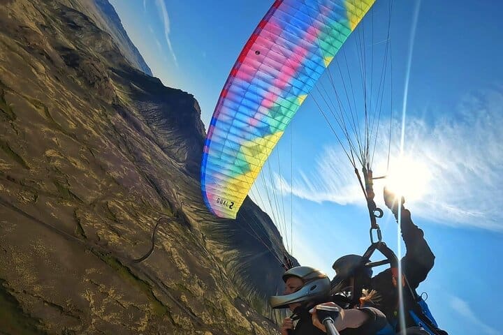 Parapente en tándem sobre los campos de lava escarpados en las montañas azules